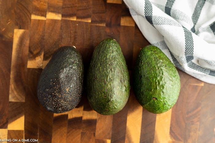 Close up image of three avocados in different stages of ripening. 