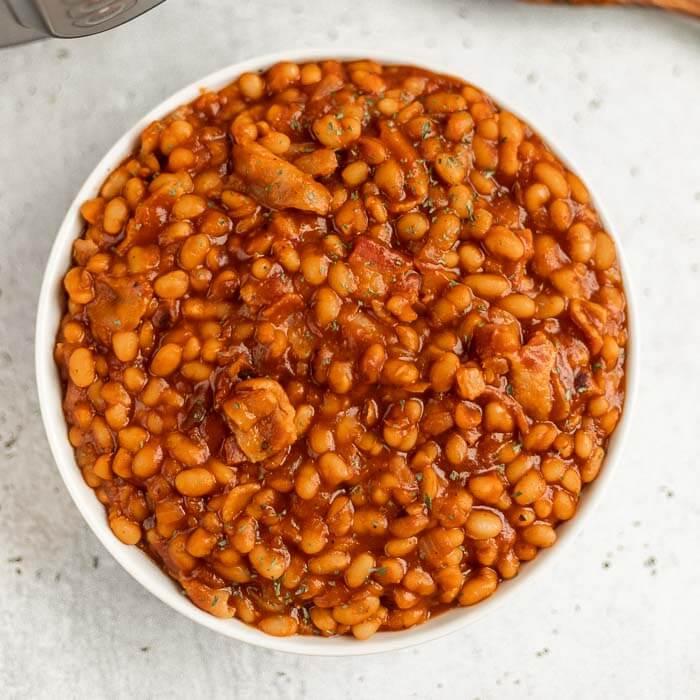 Close up image of baked beans in a white bowl.