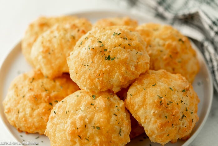 Close up image of keto cheddar biscuits  stacked on a white plate. 