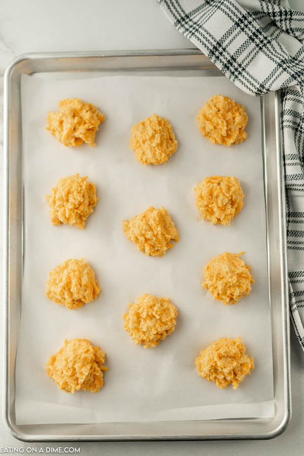 Close up image of keto cheddar biscuits   uncooked on a baking sheet. 