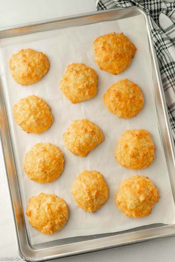 Close up image of keto cheddar biscuits  on a lined baking sheet. 