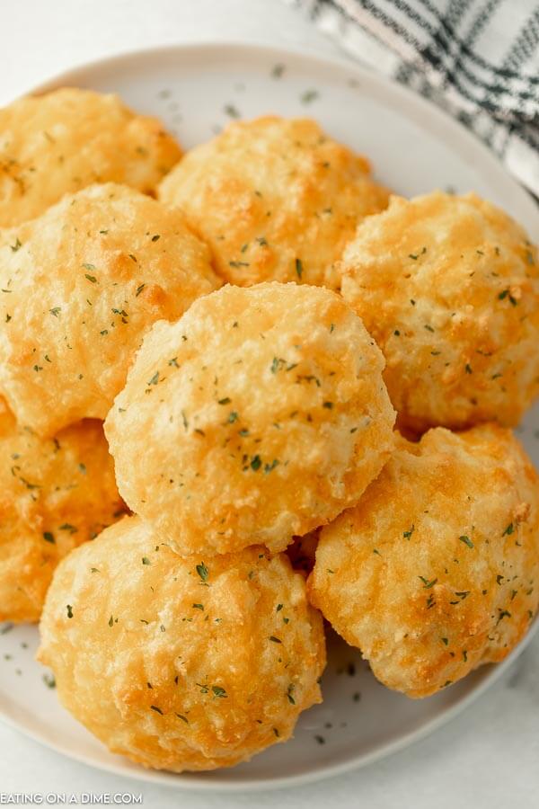 Close up image of keto cheddar biscuits  stacked on a white plate 