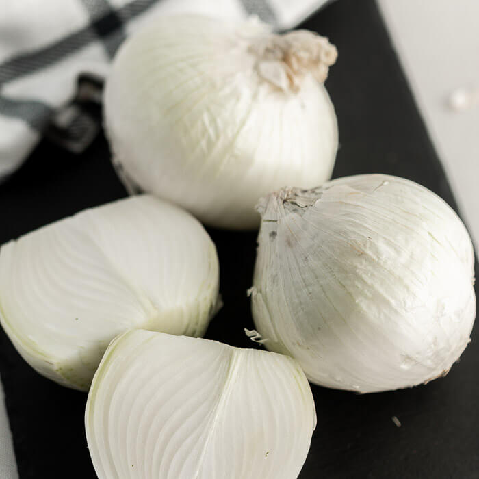 Close up image of whole onions on a cutting board.