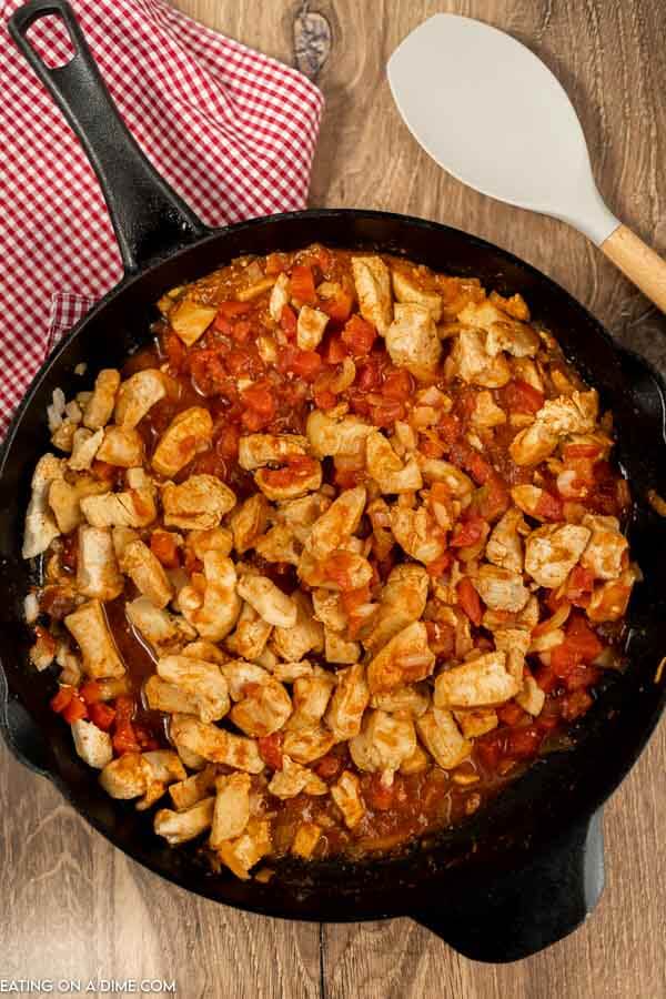 Close up image of skillet of cooked chicken with the salsa ingredients. 