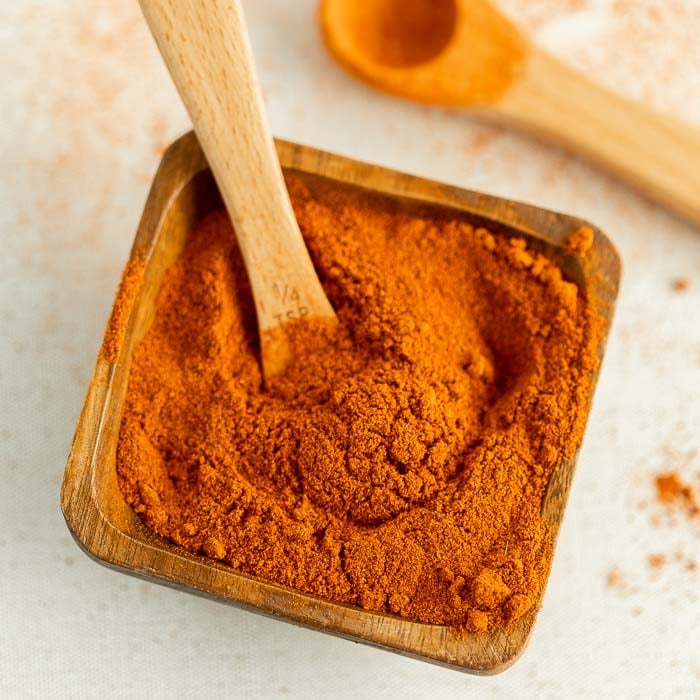 Close up image of a brown saucer with ground cayenne pepper with 2 teaspoons 