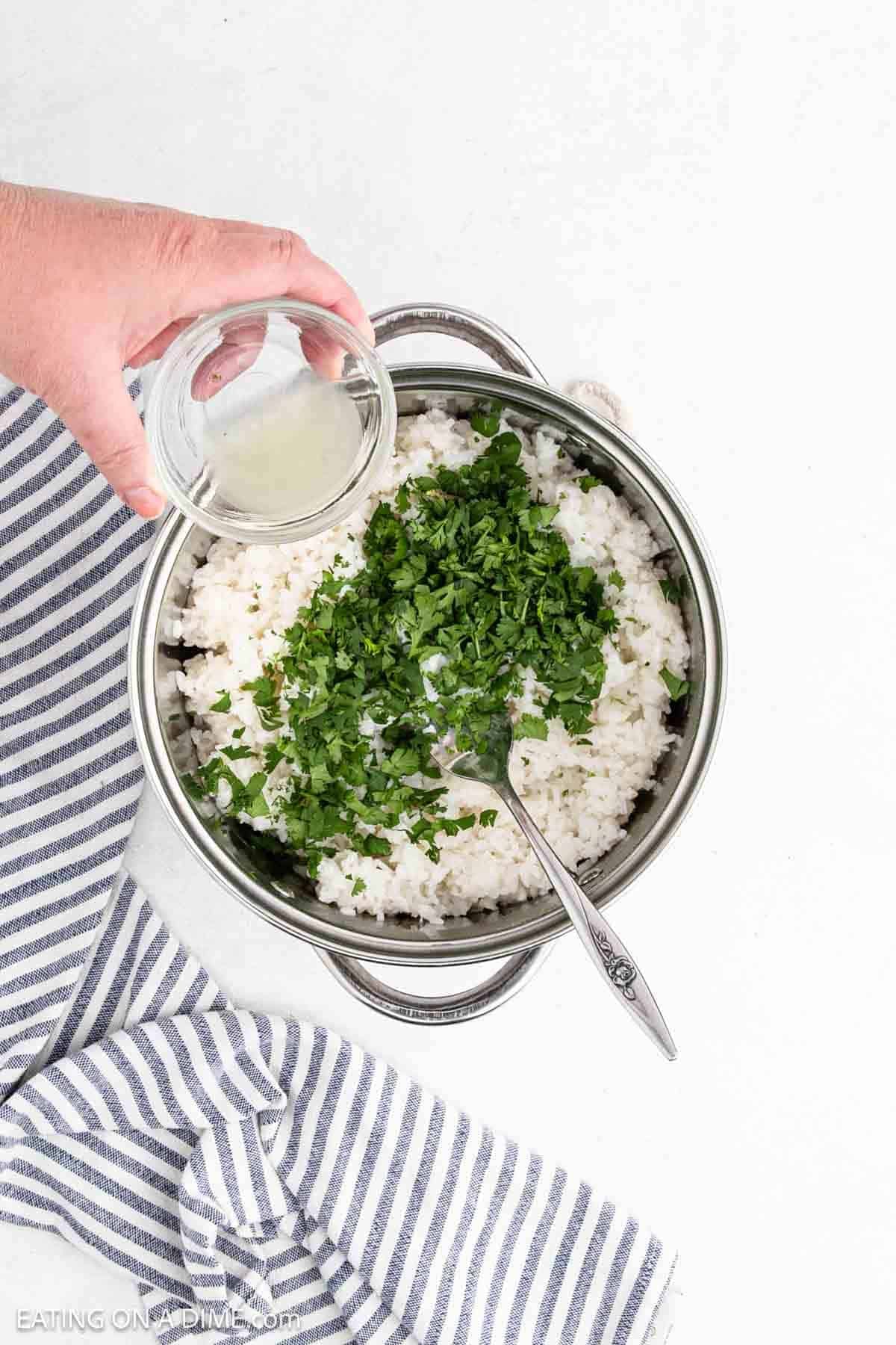 Pouring in the fresh lime juice over the cilantro and white rice in the large pot.