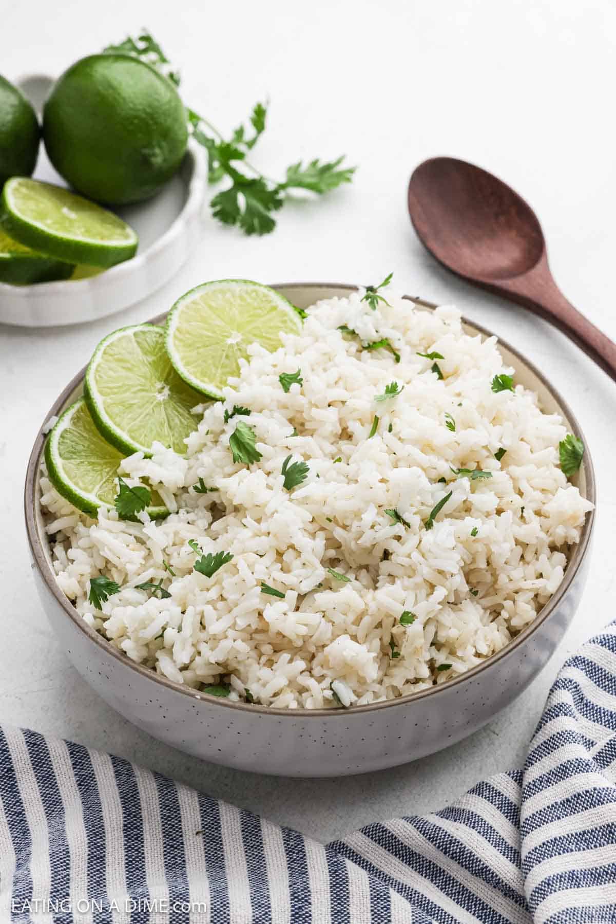 Rice mixed with cilantro in the bowl garnished with slices of fresh lime.