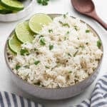 Cilantro lime rice in a bowl garnished with slices of fresh lime.