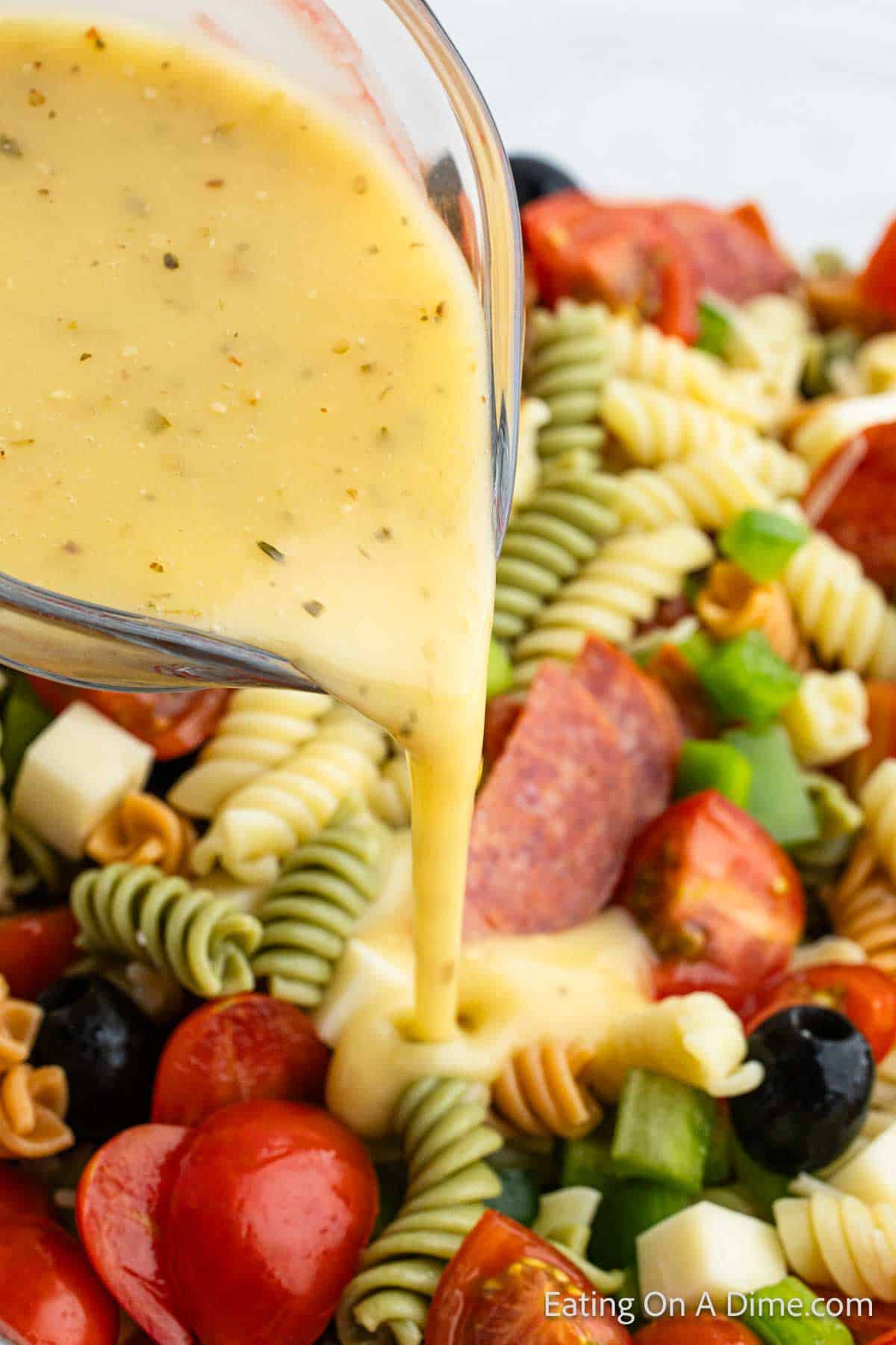 Pouring salad dressing over the pasta salad mixture
