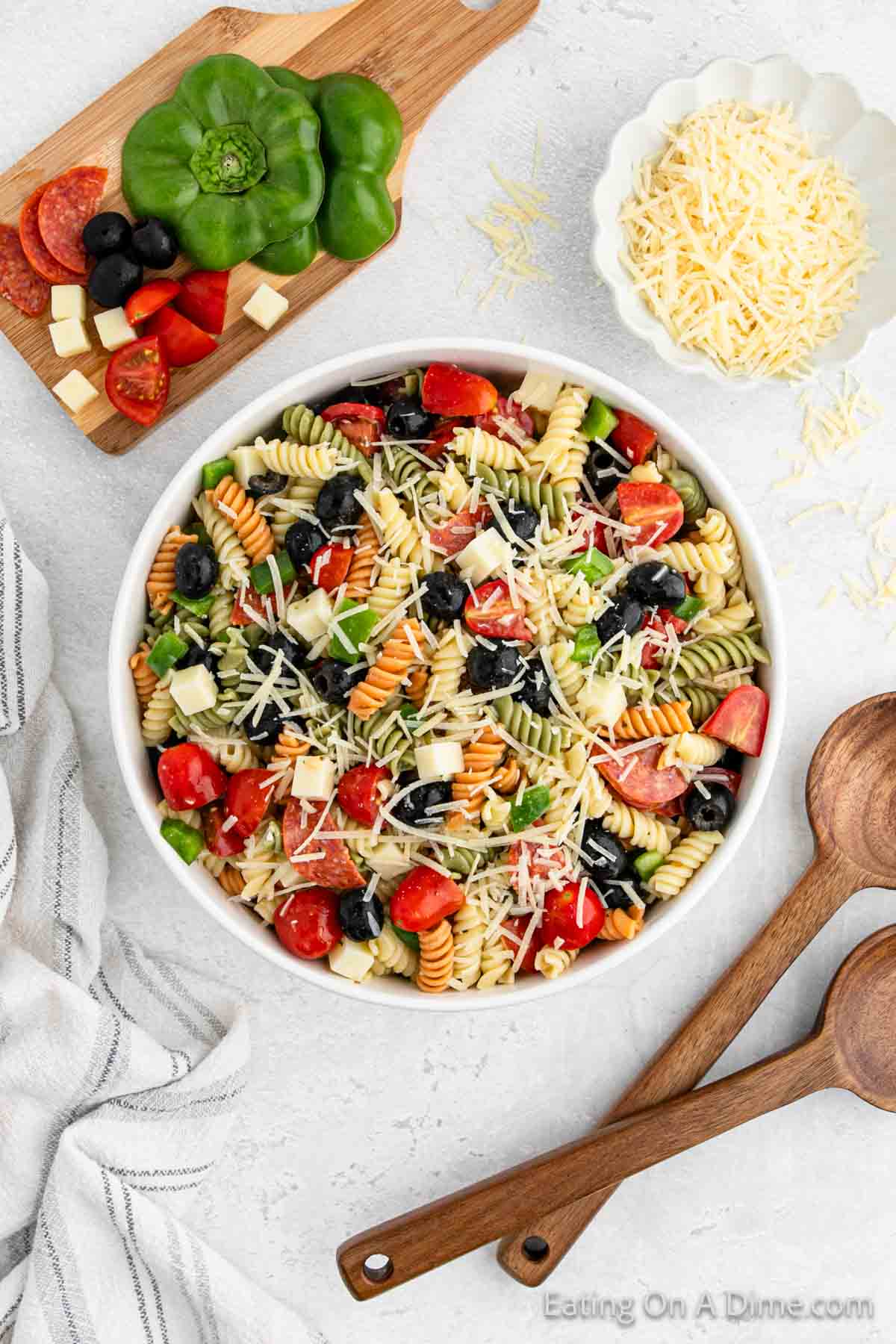 Italian Pasta Salad in a bowl with a cutting board with bell peppers, pepperoni, and vegetables