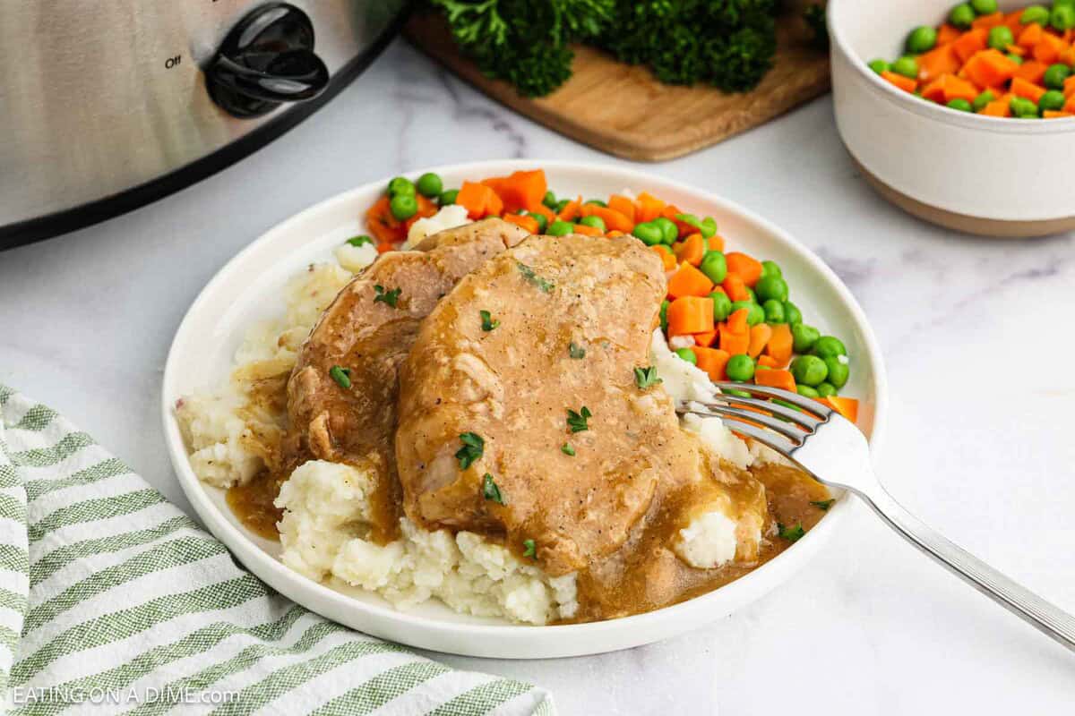 Pork Chops and gravy on a plate with carrots and peas