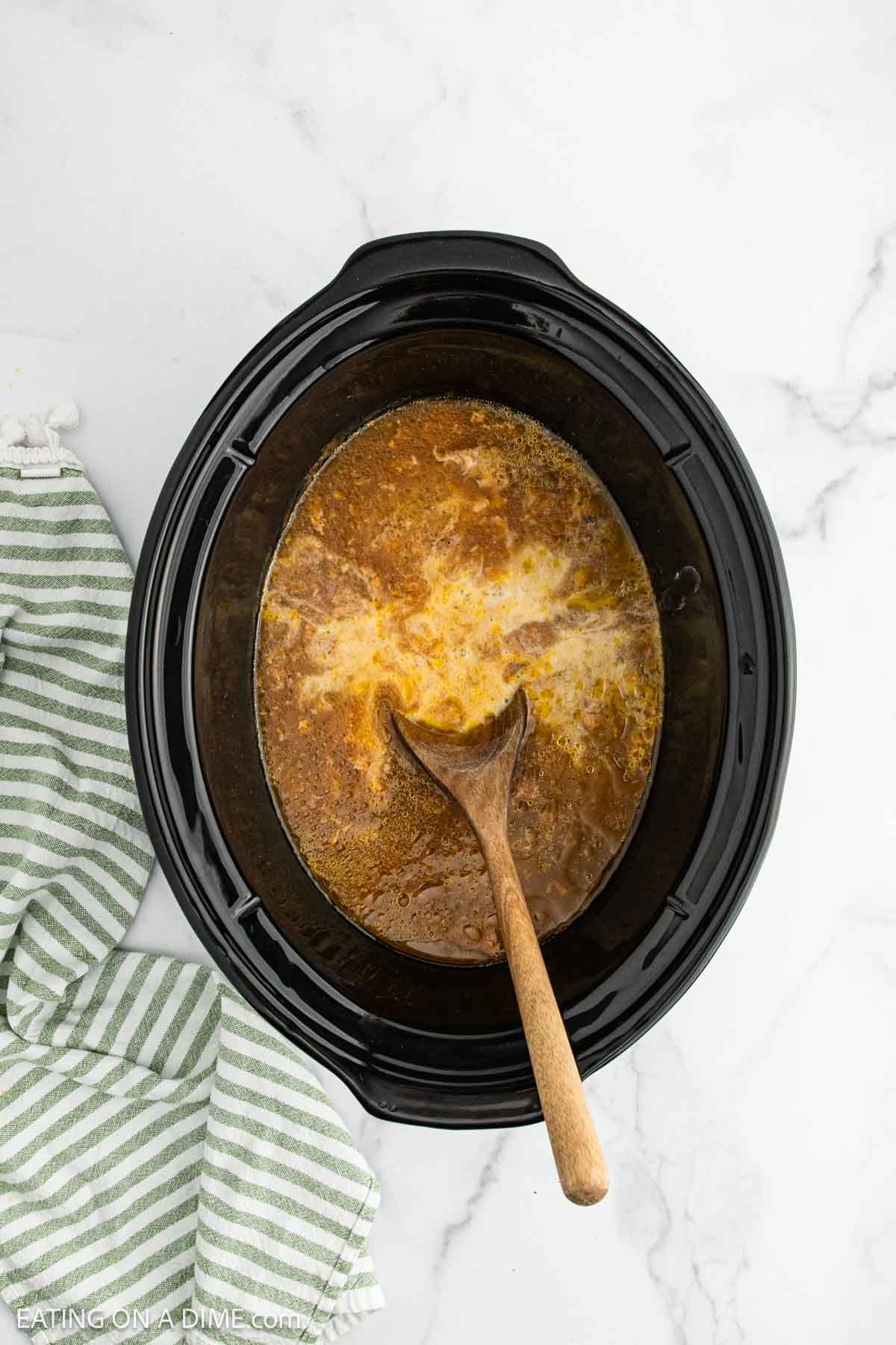 Stirring in the cornstarch slurry in the slow cooker with a wooden spoon