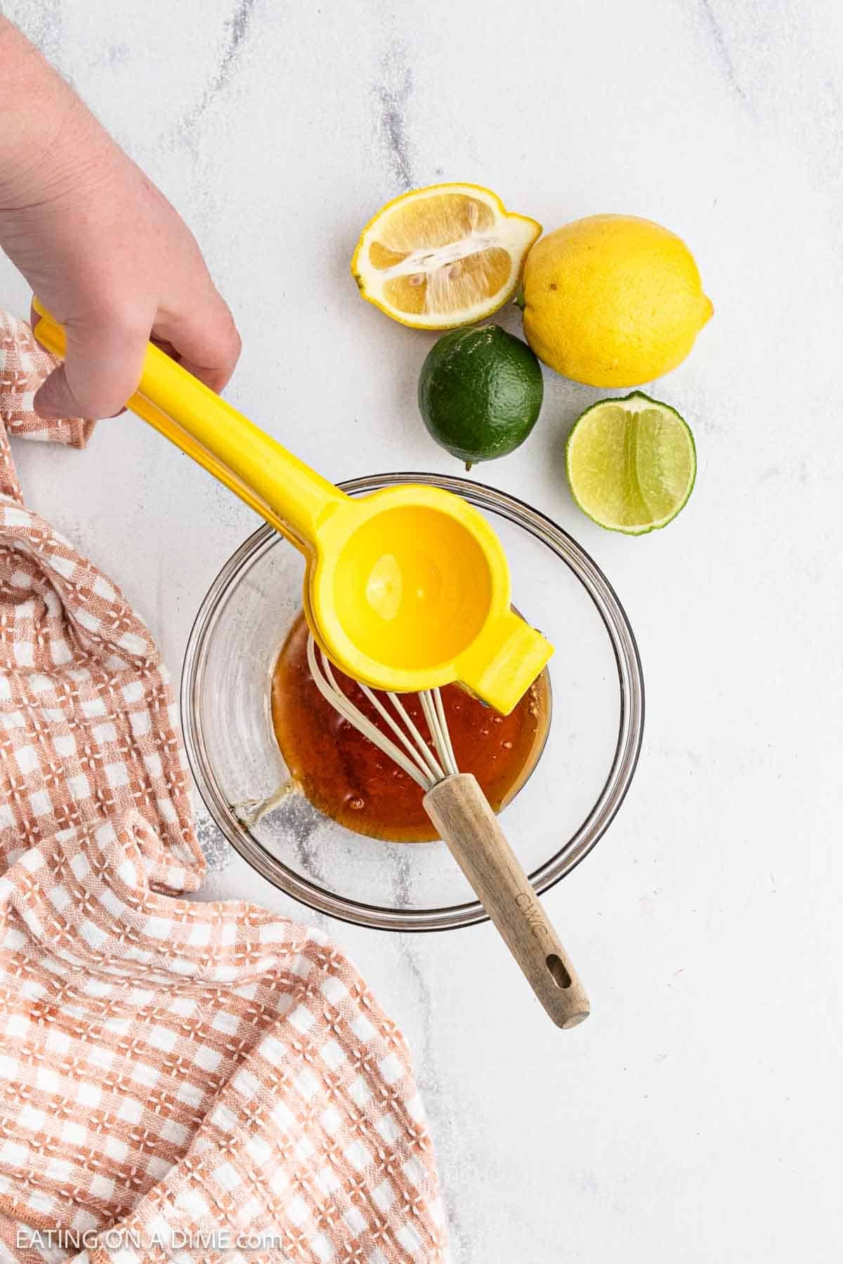 Fresh lemon being a squeezed over a bowl of honey.