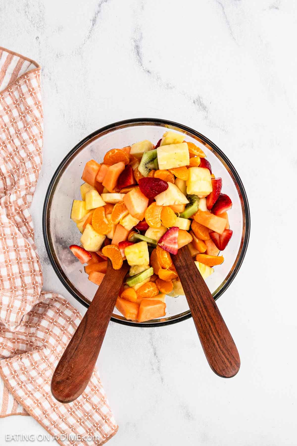 A mixture of fresh fruit in a bowl with wooden spoons.