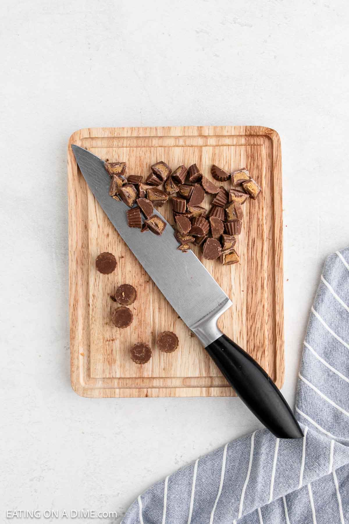 Chopping the Reese's Peanut Butter Cups in half with a knife on a cutting board