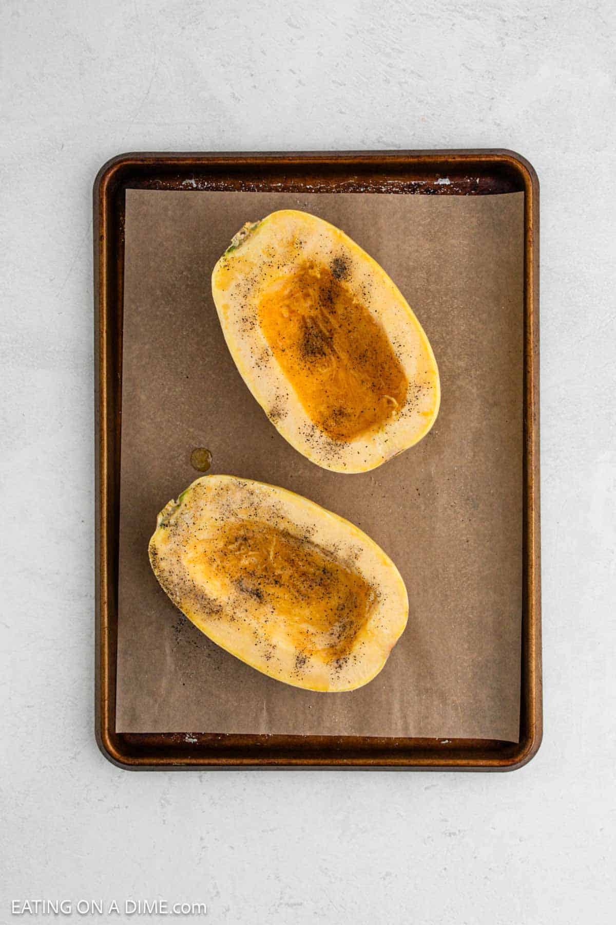 Seasoned uncooked squash on a baking sheet.