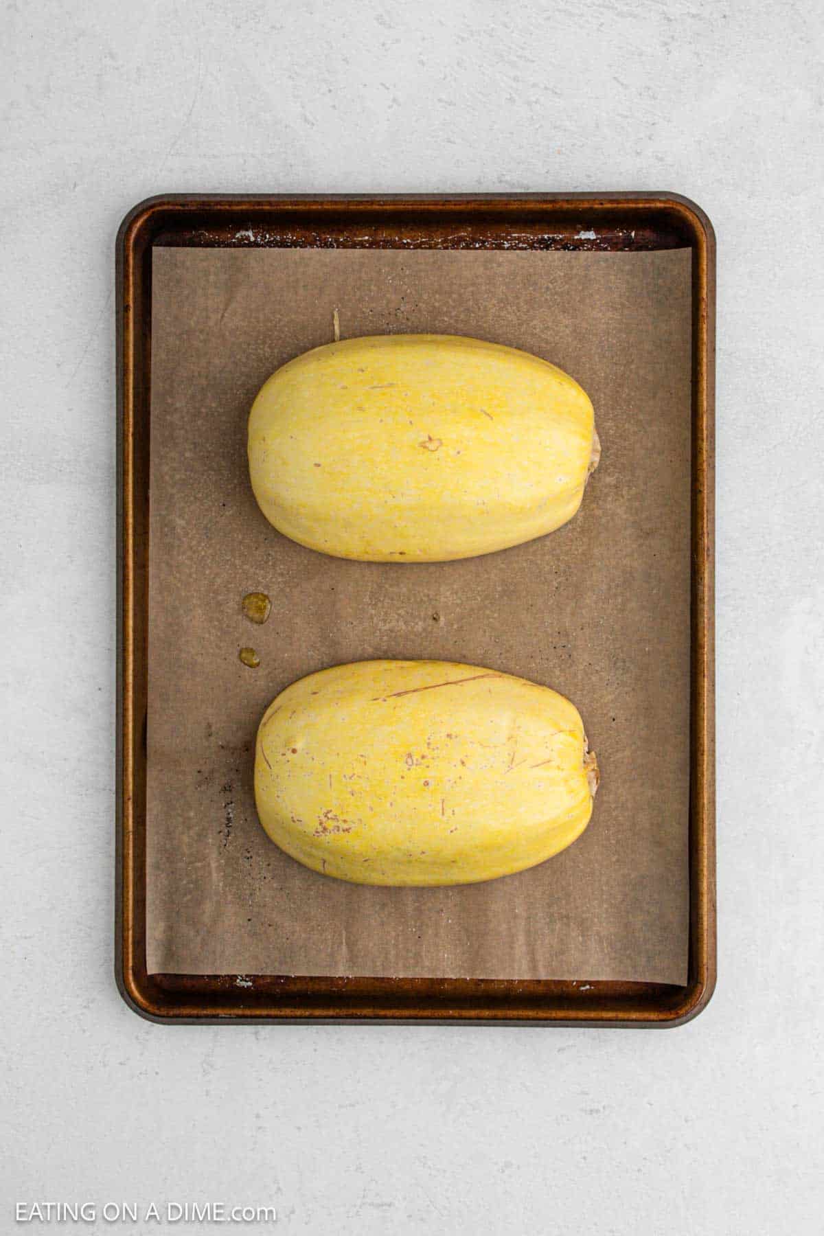 Squash cut in half on a baking sheet.