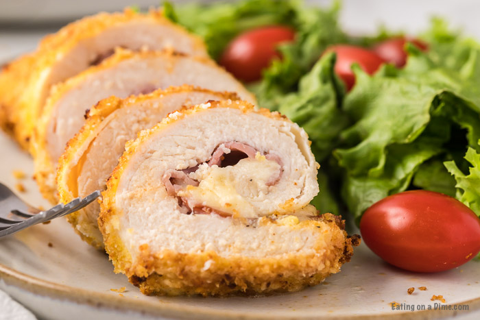 Close up image Chicken Cordon Bleu with a side salad on a plate. 