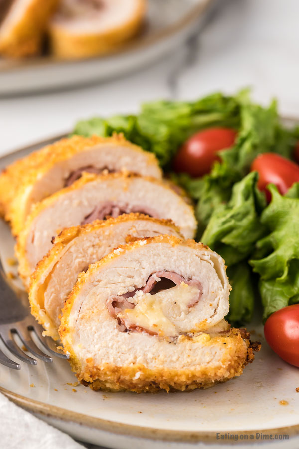 Close up image Chicken Cordon Bleu with a side salad on a plate. 