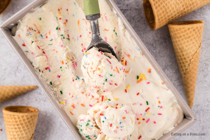 Birthday Cake Ice Cream in a loaf pan with a serving on a ice cream scoop. 