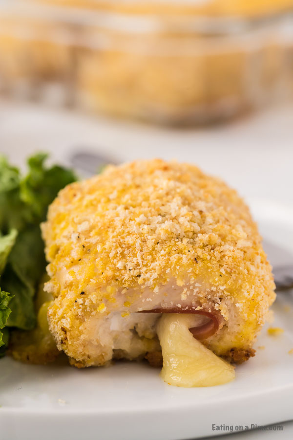 Close up image of chicken cordon bleu on a white plate with a side salad. 