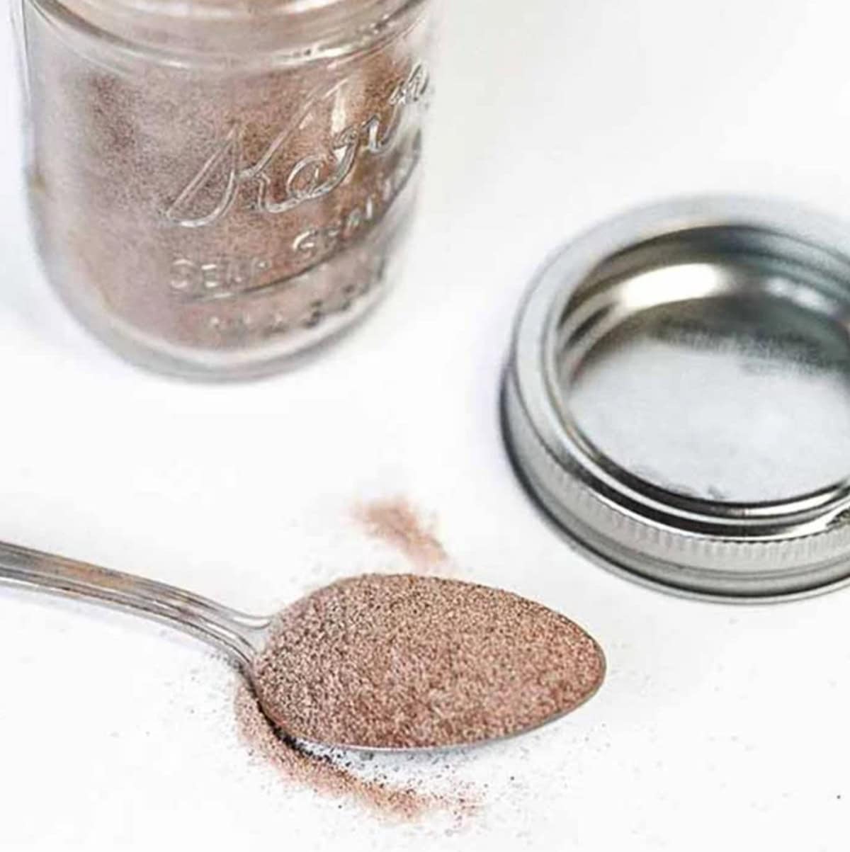 A jar of cinnamon sugar mixture with a spoon full of the mixture next to it.
