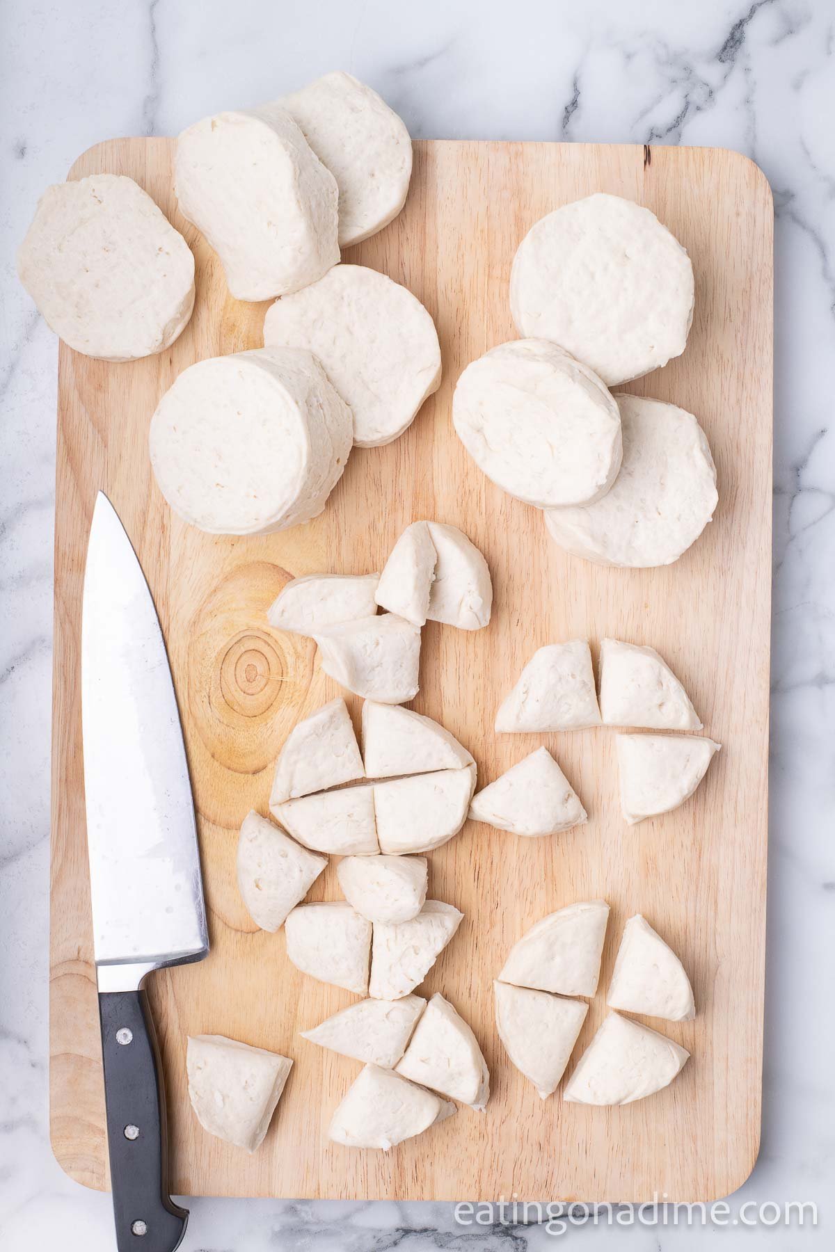 The biscuits placed on a cutting board and cut into quarters.  