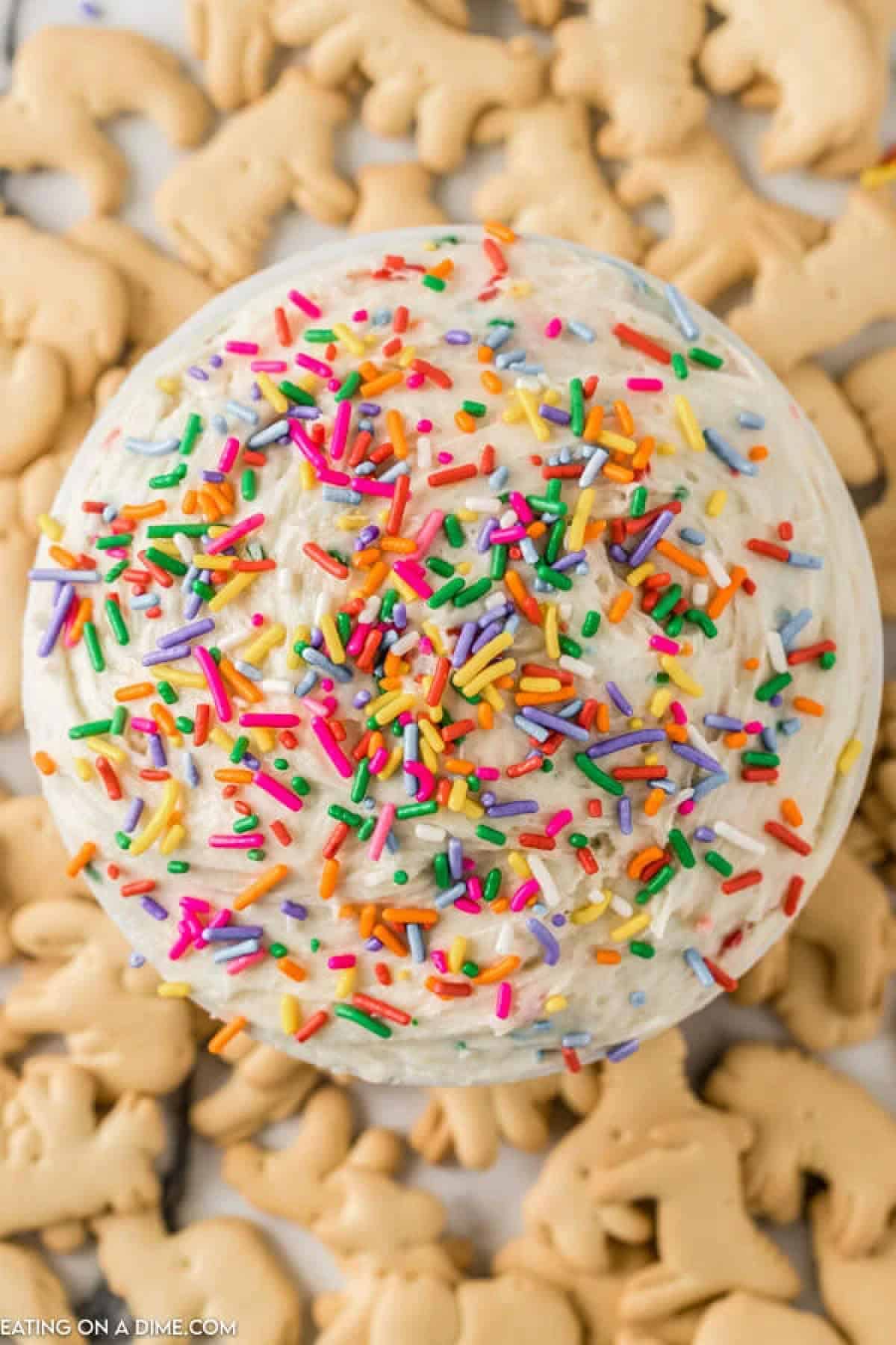 Close up image of funfetti dip in a white bowl with sprinkles and animal crackers on the side.