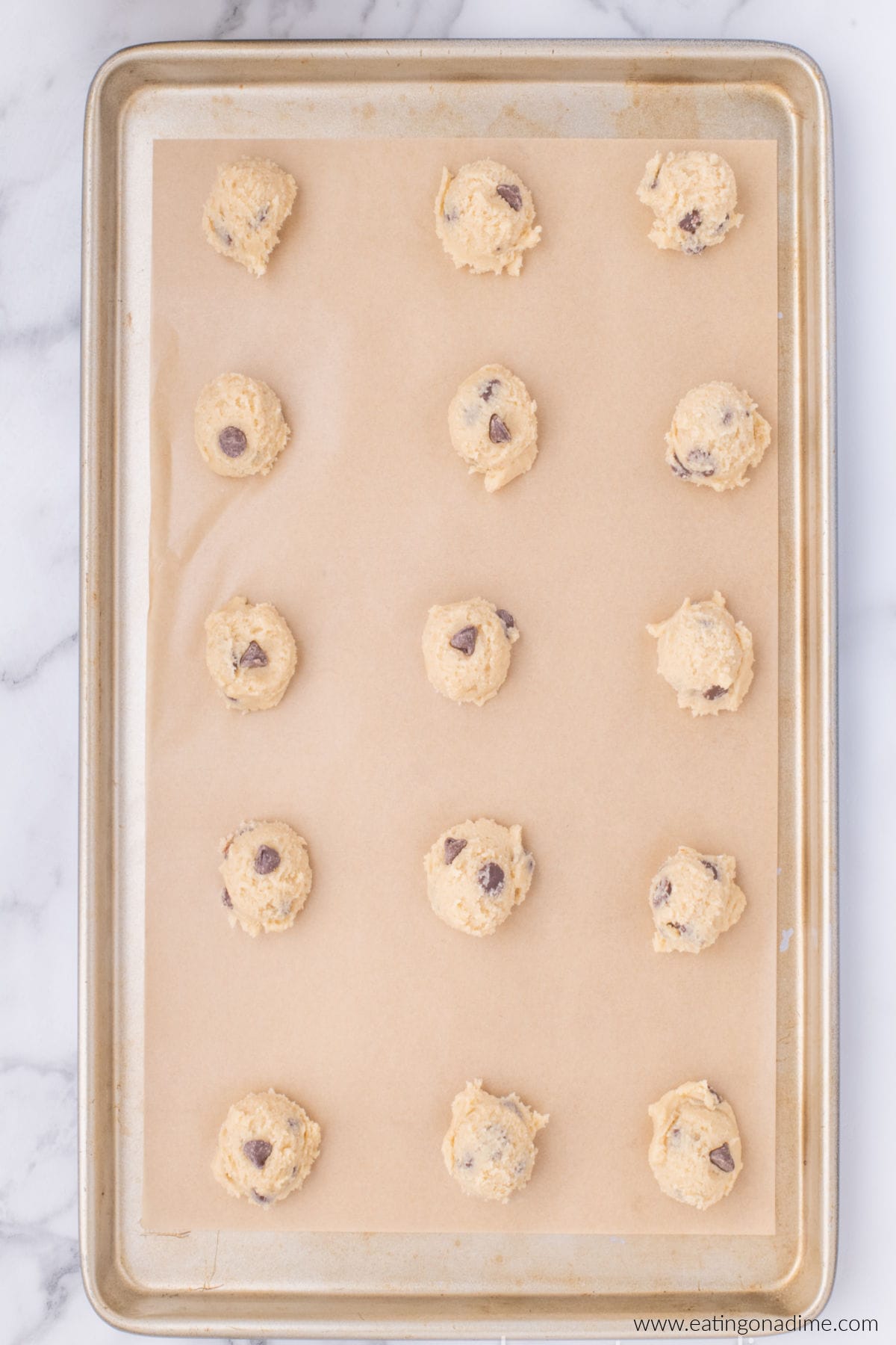 Cookie dough formed into small bowls and placed on a baking sheet lined with parchment paper.