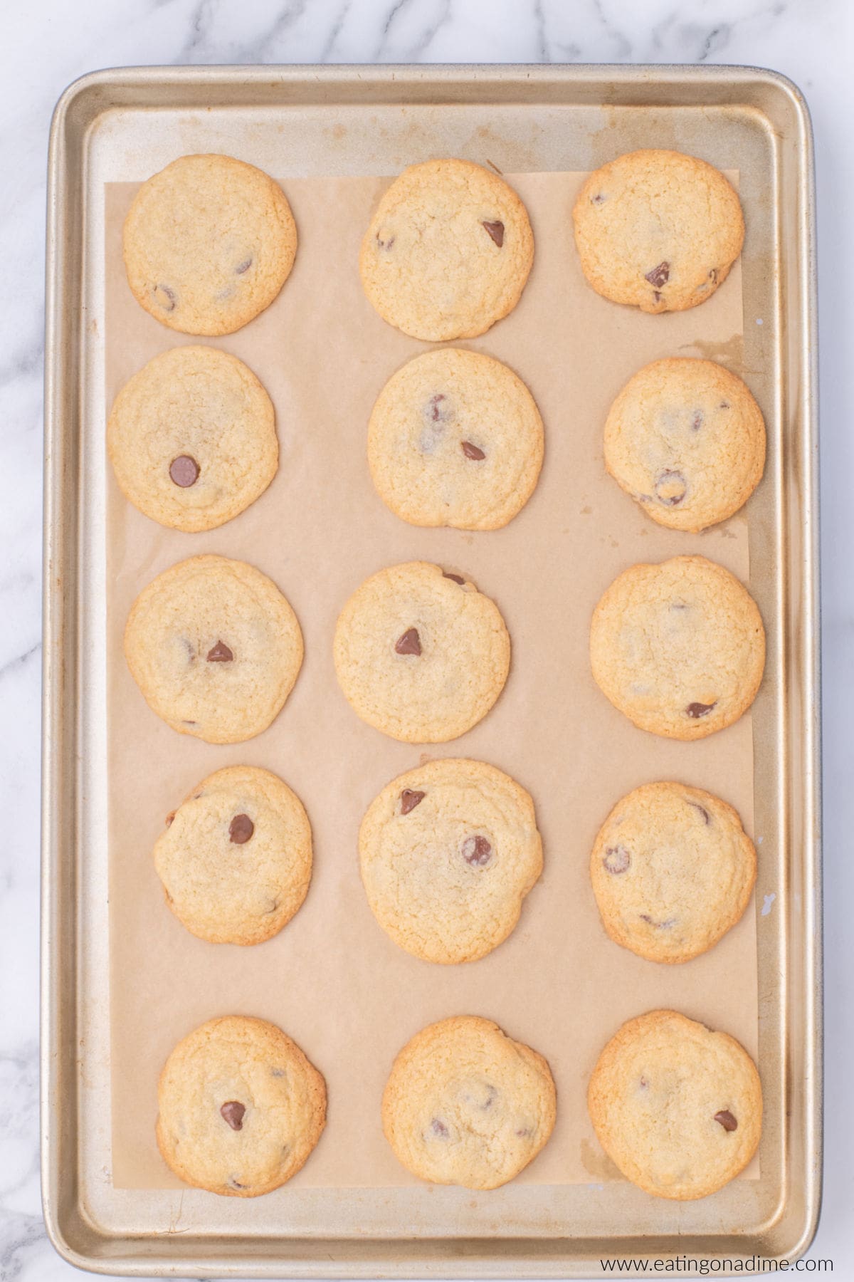 Baked chocolate chip cookies on a baking sheet with parchment paper.