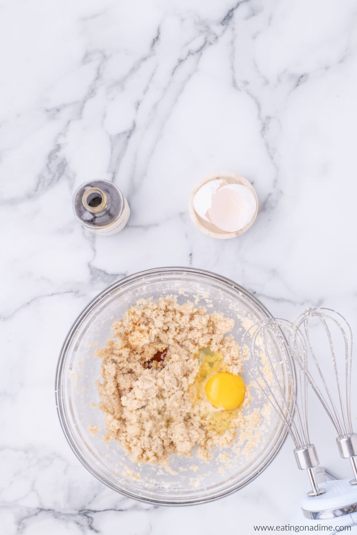 Whole egg and vanilla added to the sugar mixture in a bowl.