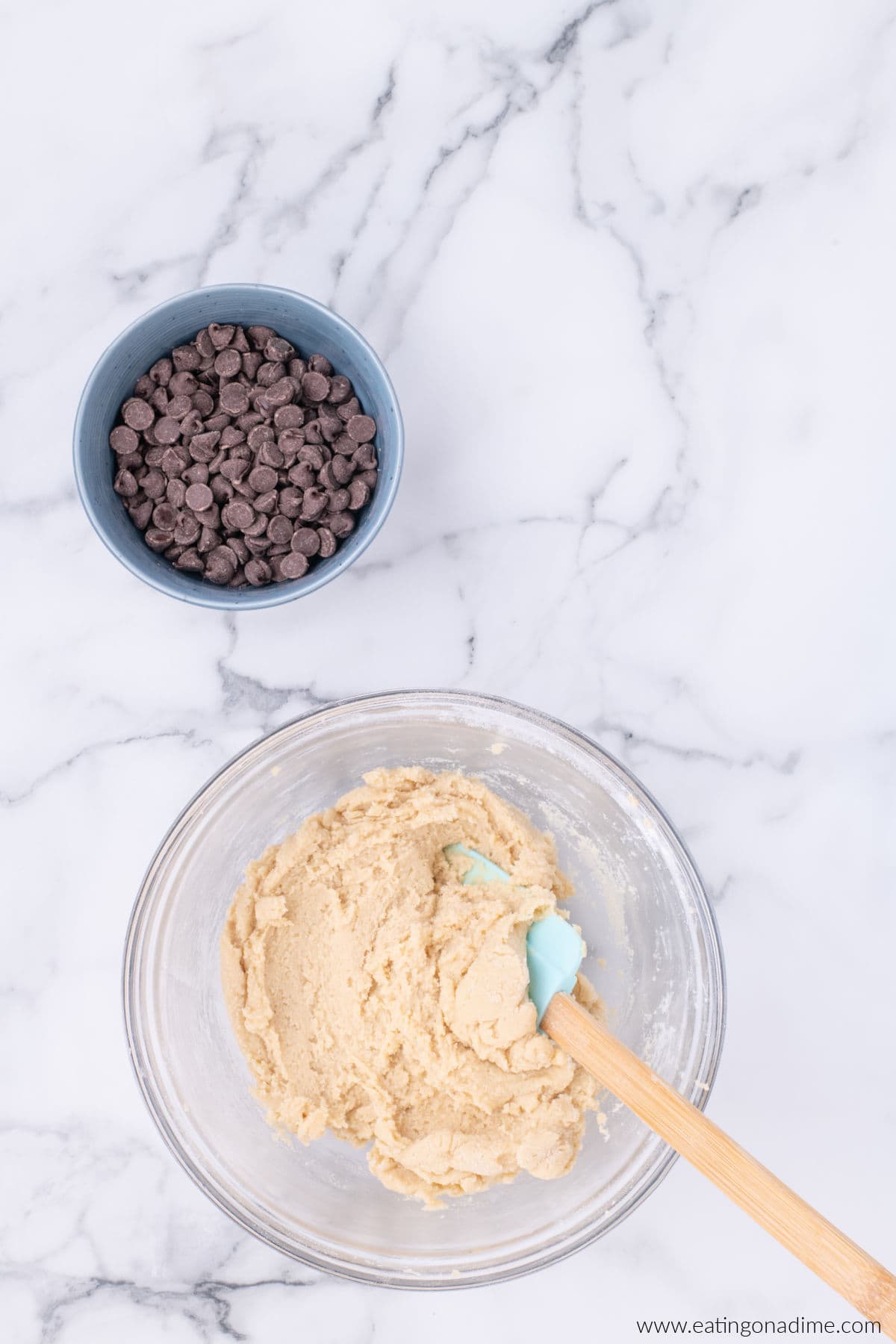 Cookie dough in a bowl with a small bowl of chocolate chips nearby.