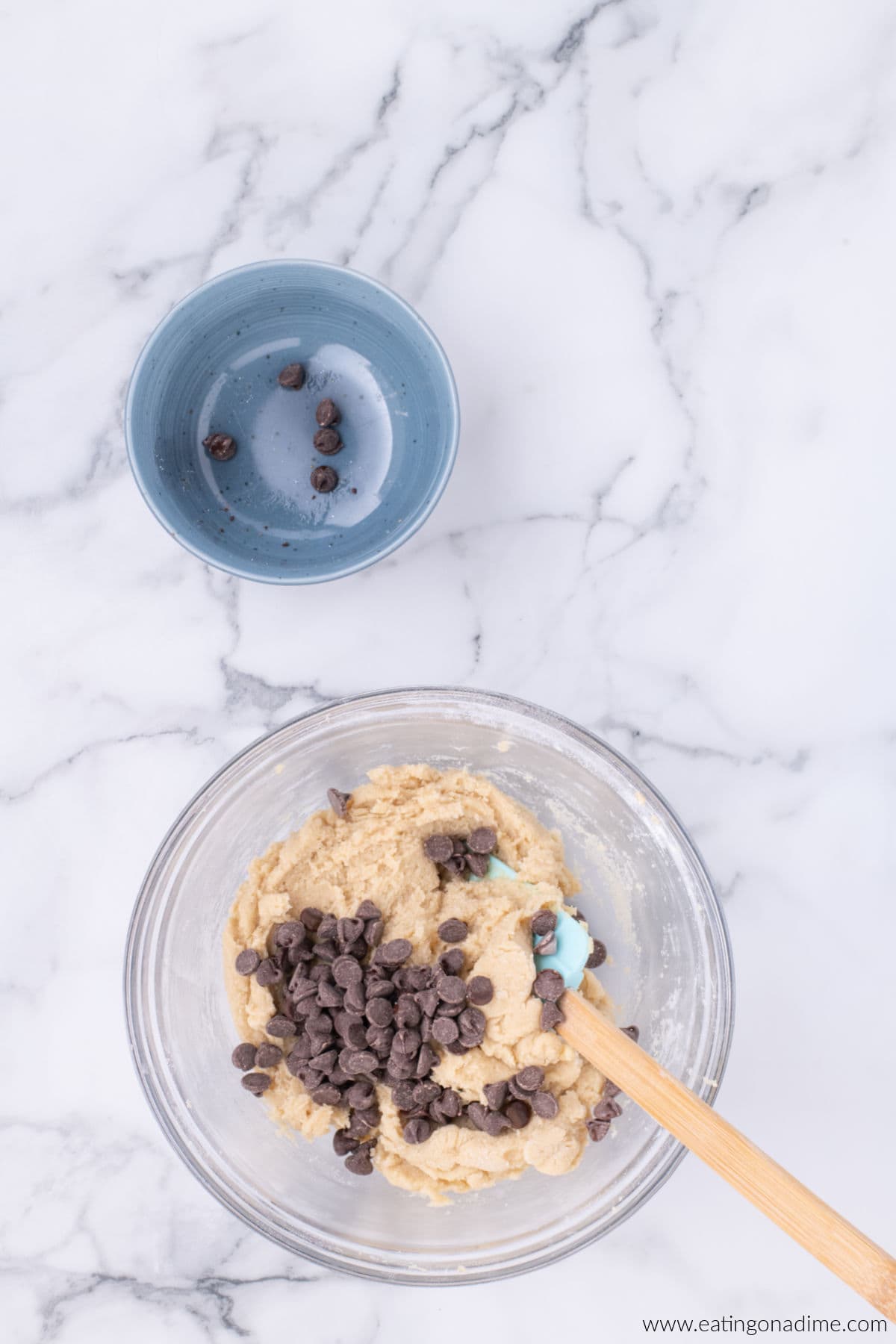 Chocolate chips added to the cookie dough in a bowl.