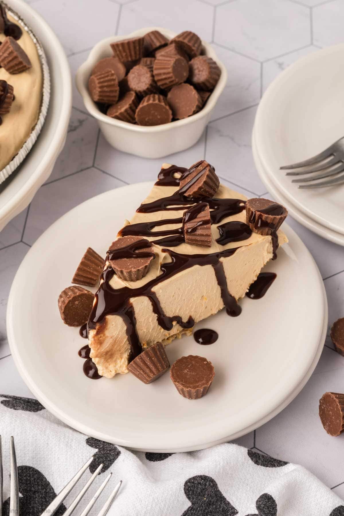 Slice of peanut pie topped with mini Reese's Peanut Butter cups and a drizzle of chocolate syrup