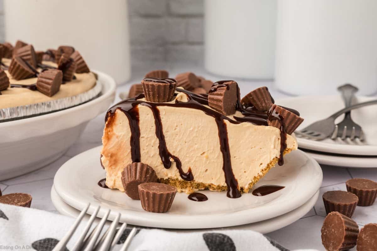Slice of peanut butter pie on a plate topped with chocolate syrup and mini peanut butter cups