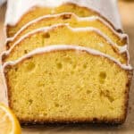 Sliced lemon pound cake with a light glaze on top, showing a moist and dense yellow interior. A lemon wedge—often discussed as the best substitute for lemon juice—is partially visible in the foreground.