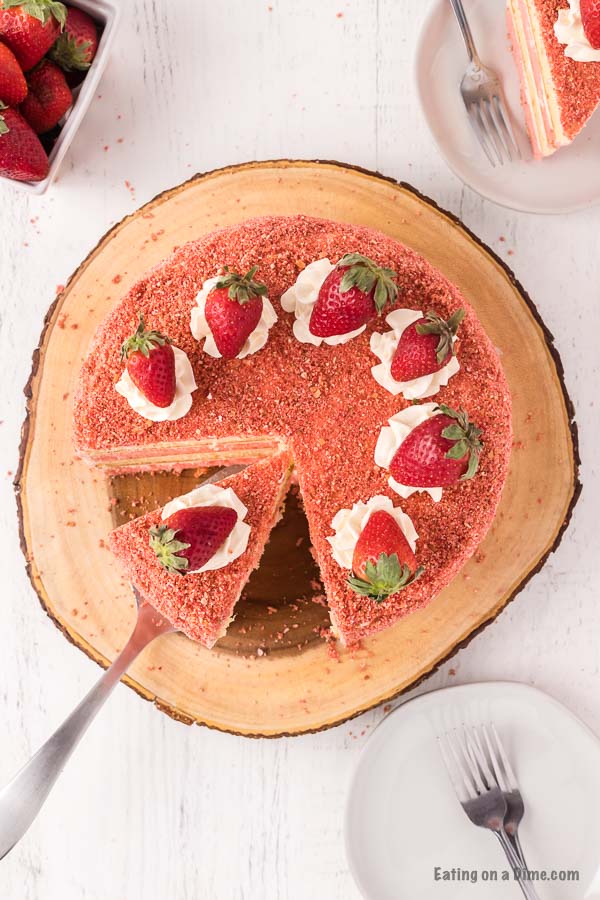 Strawberry Crunch Cake topped with fresh strawberries with a serving a spatula