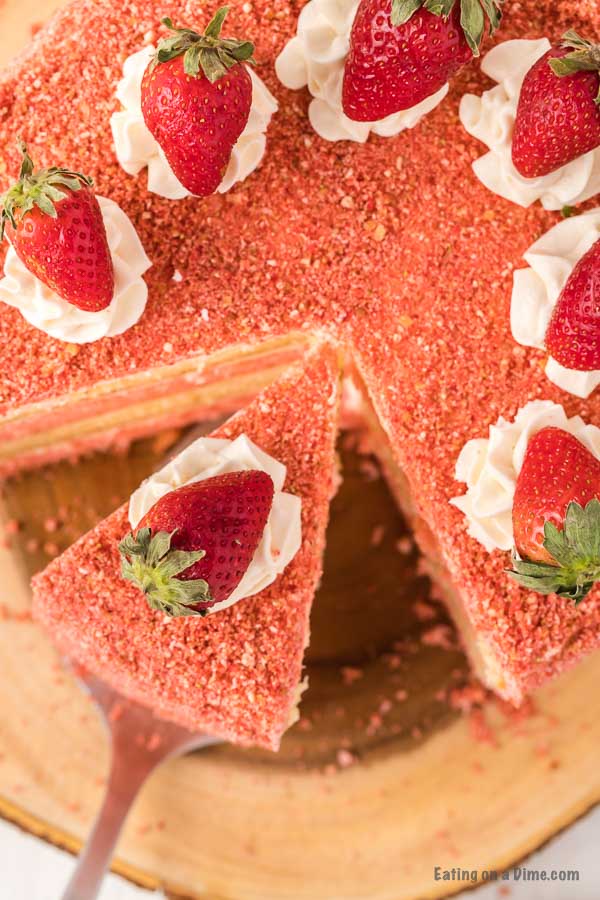 Strawberry Crunch Cake topped with fresh strawberries with a serving a spatula