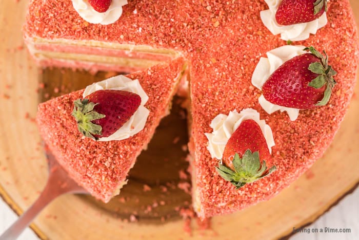 Strawberry Crunch Cake topped with fresh strawberries with a serving a spatula