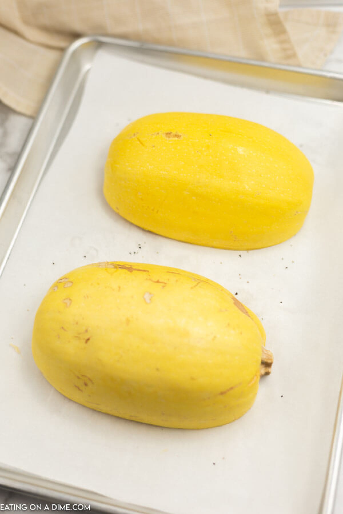 Close up image of spaghetti squash face down on a cooking sheet. 