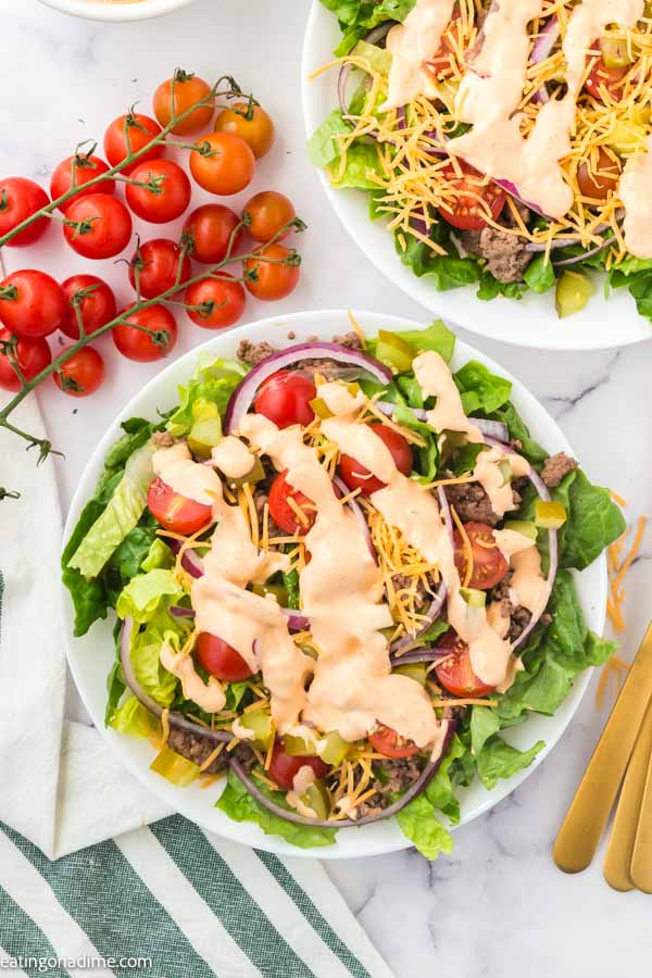 Close up image of big mac salad on a plate with cherry tomatoes on the side.
