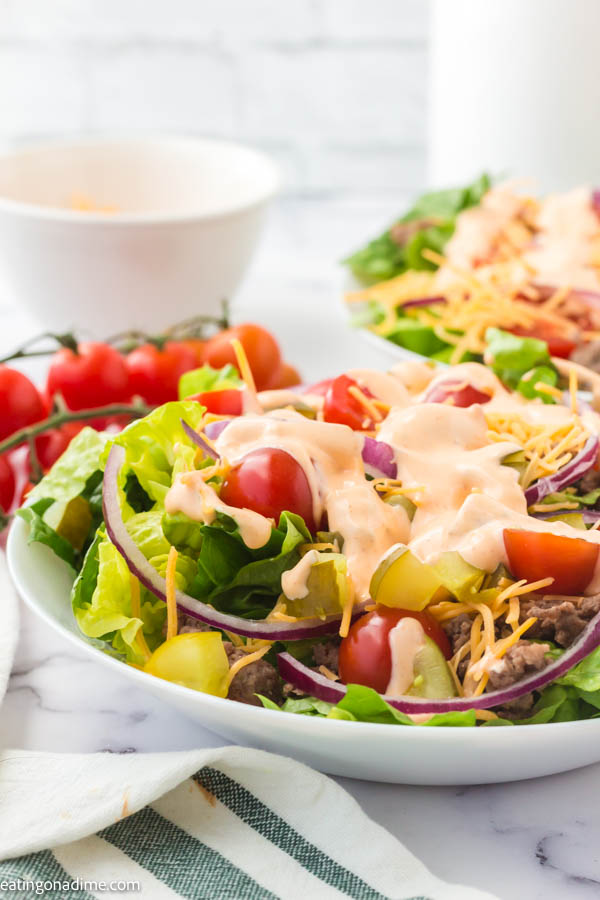 Close up image of big mac salad on a plate with cherry tomatoes on the side.