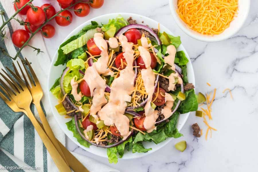 Close up image of big mac salad on a plate with cherry tomatoes on the side.