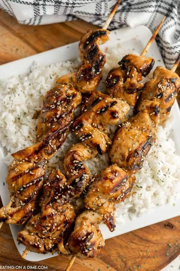 Chicken on a stick on rice on a plate. 