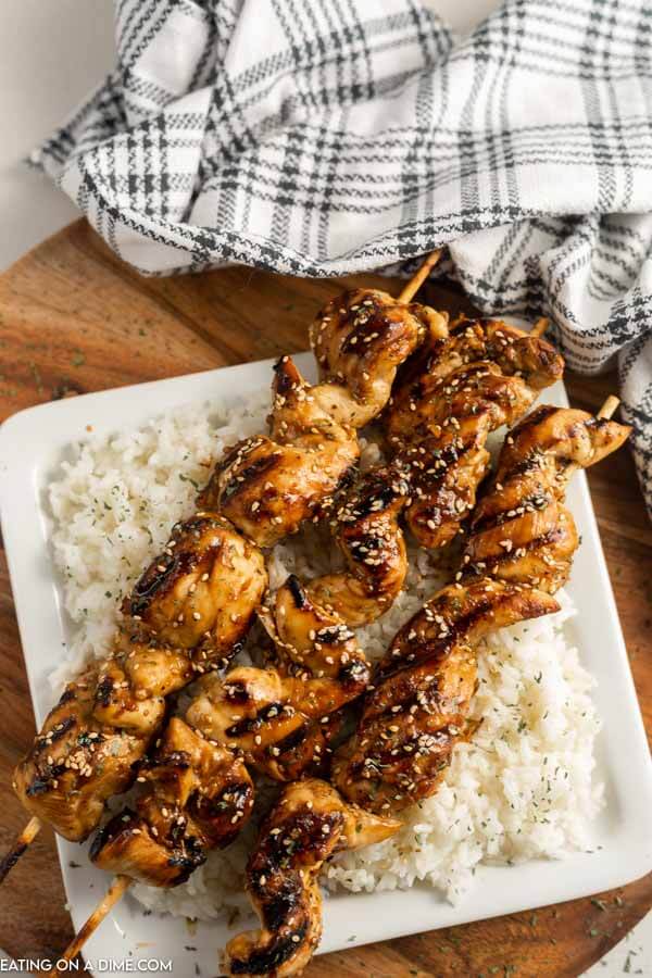 Chicken on a stick on rice on a plate. 