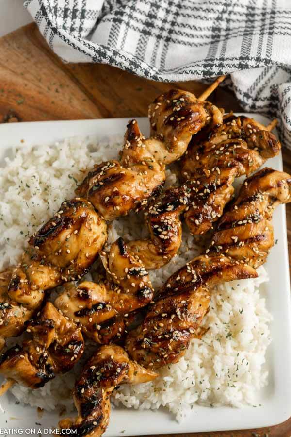 Chicken on a stick on rice on a plate. 