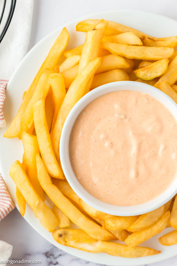 Close up image of big mac sauce in a white bowl with a side of french fries. 
