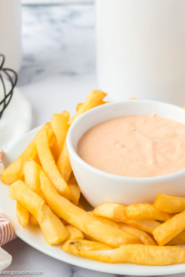 Close up image of big mac sauce in a white bowl with a side of french fries. 