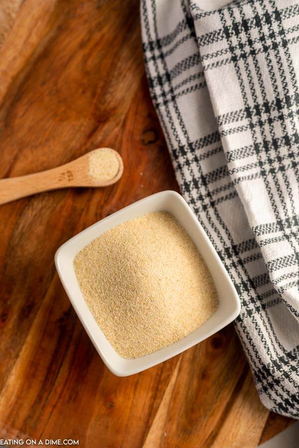 Close up image of onion powder in a dish with a ¼ teaspoon. 