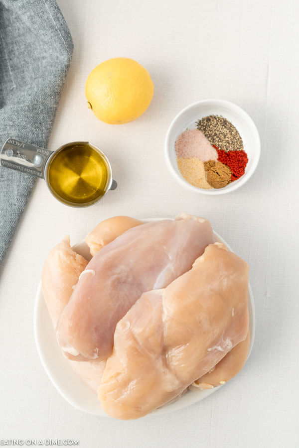 Ingredients for grilled chicken marinade - chicken breasts, salt and pepper, paprika, garlic powder, cumin, parsley, olive oil, lemon